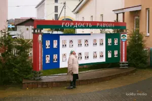 Менш лістоў — больш даверу? Разбіраемся, чаму чыноўнікі Гродзеншчыны сталі атрымліваць менш скаргаў Жанчына глядзіць на дошку гонару "Гонар раёна" недзе ў Астравецкім раёне © LookByMedia